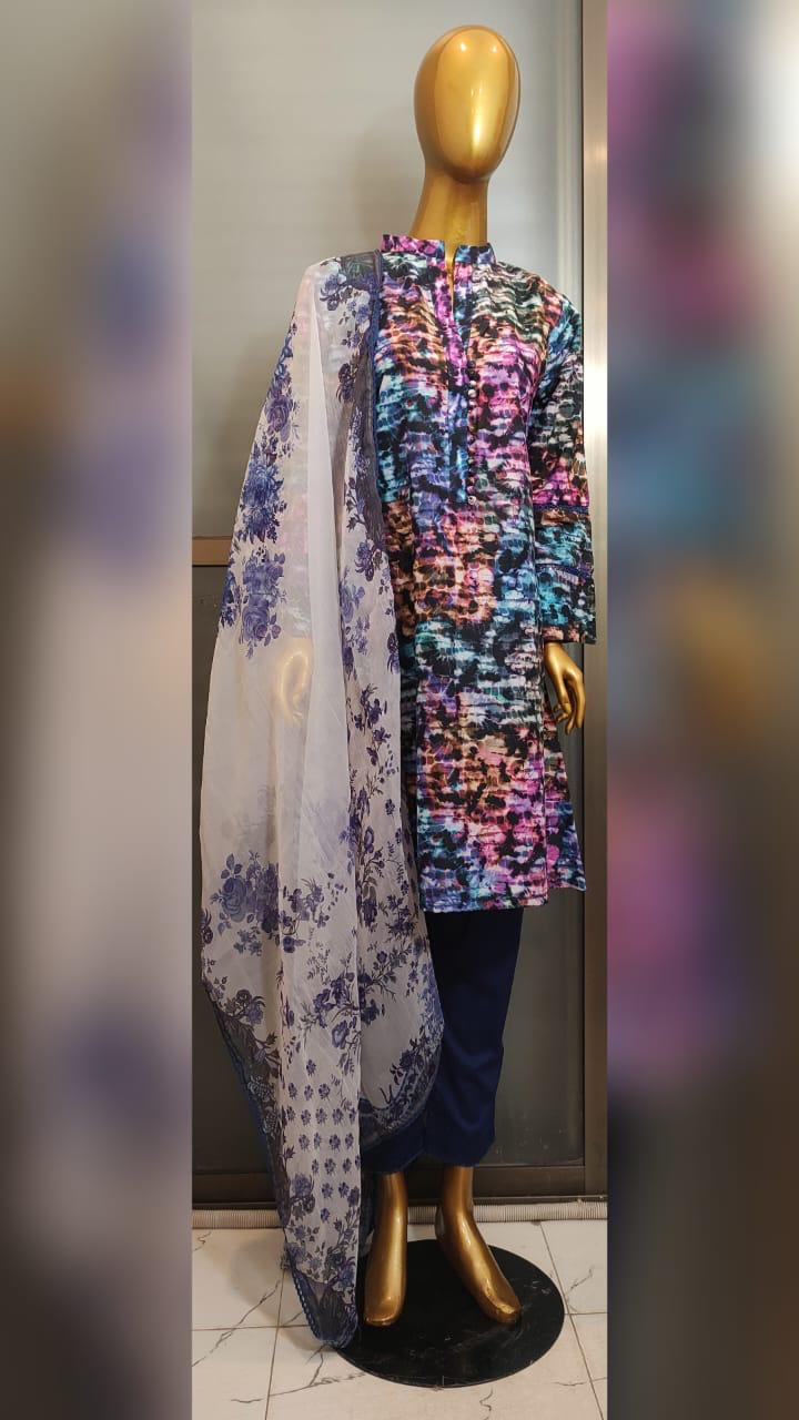 Mannequin wearing a colorful floral top with a sheer white scarf and dark pants.