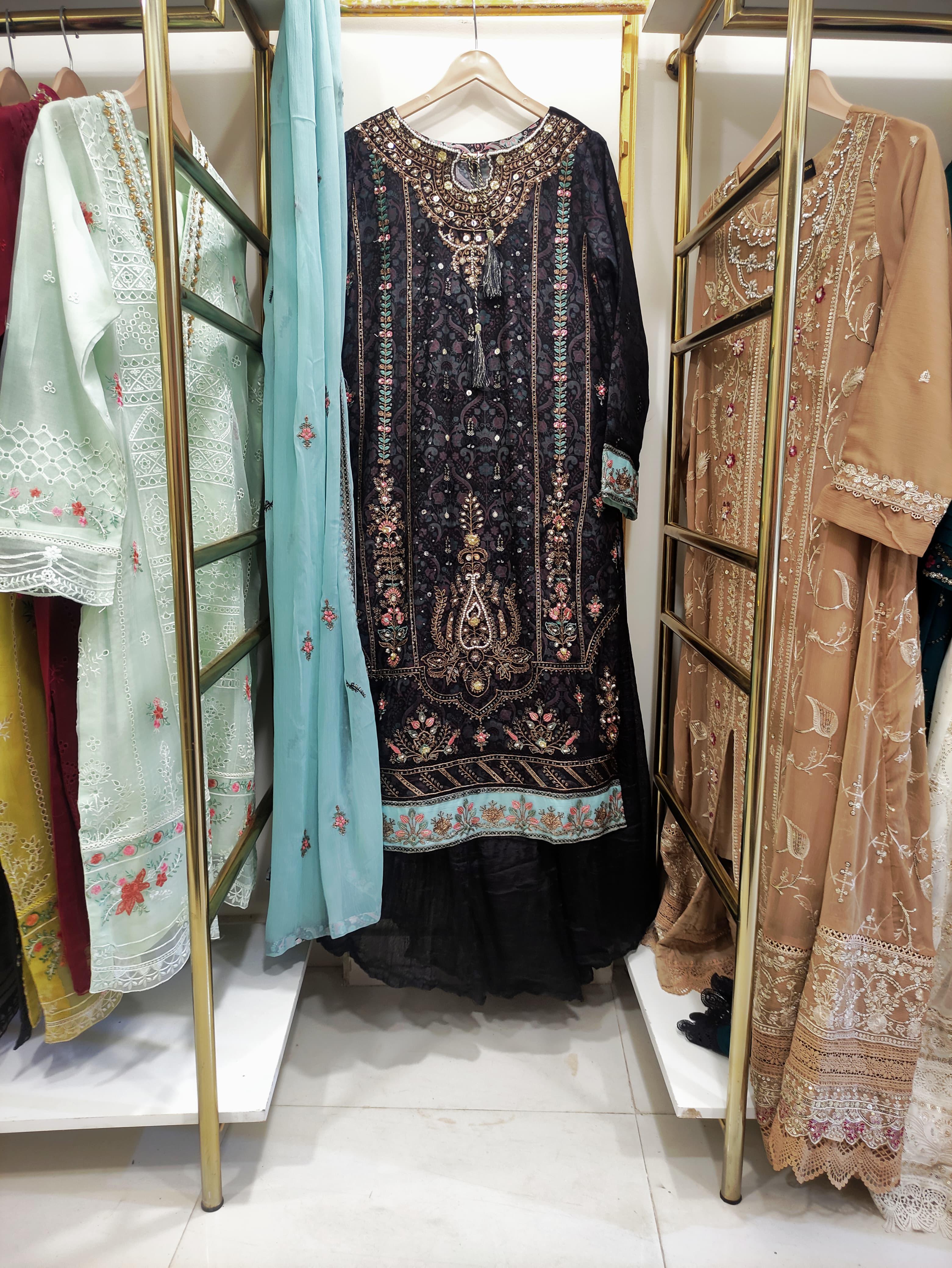 Display of traditional embroidered dresses on hangers in a store.