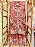 Pink embroidered traditional outfit on a hanger with a blurred background